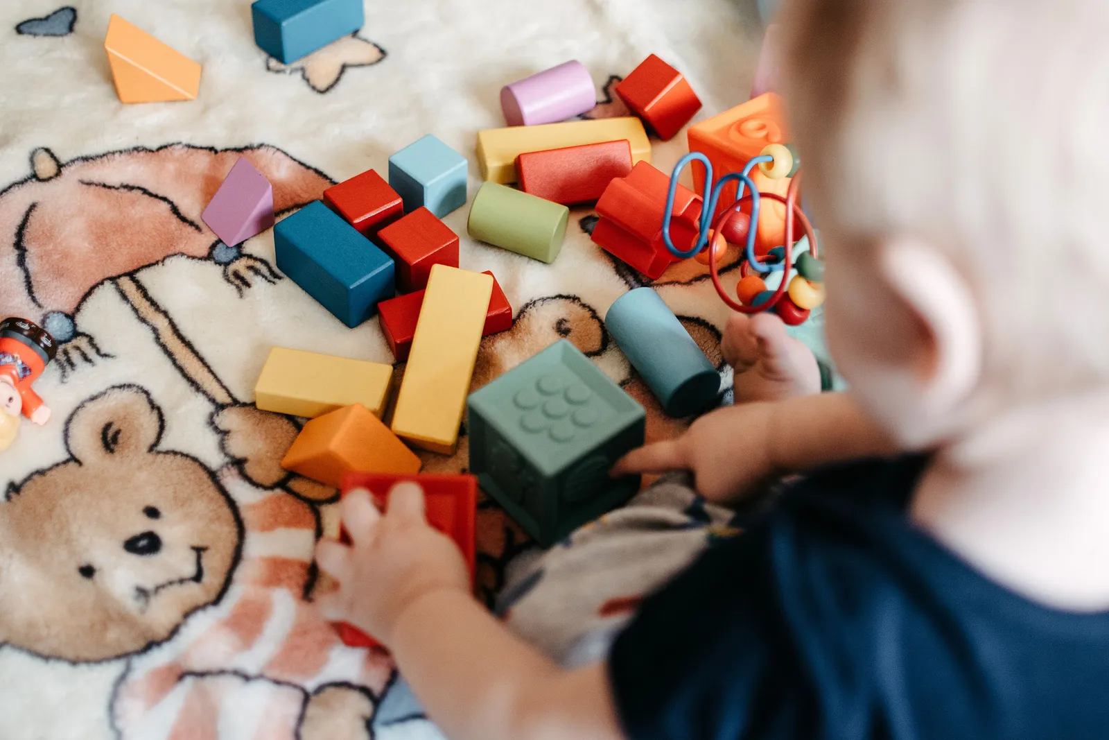Criança brincando com blocos de construção coloridos sobre um cobertor estampado