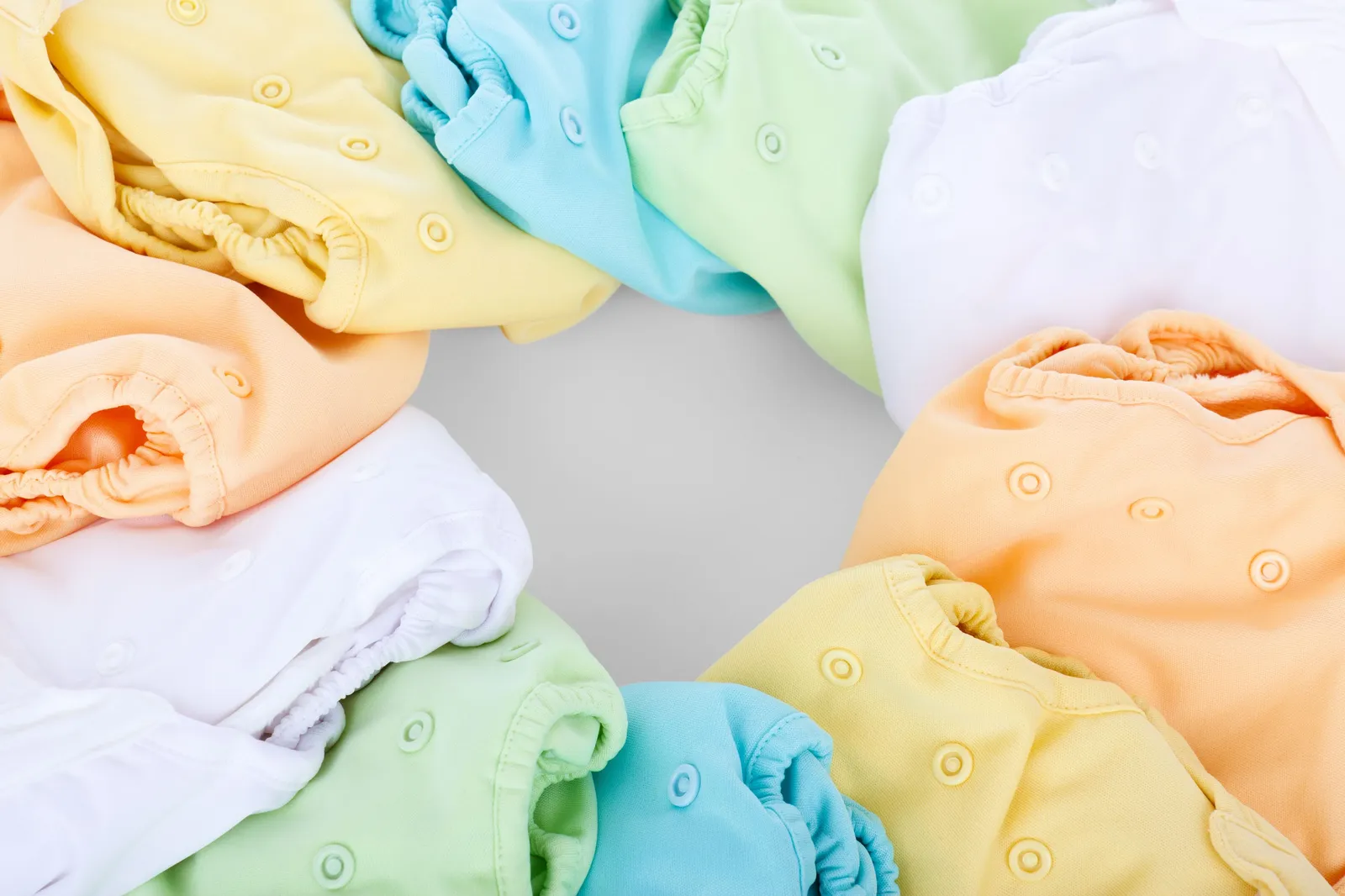 Fraldas de pano coloridas dispostas em formato circular sobre uma superfície clara