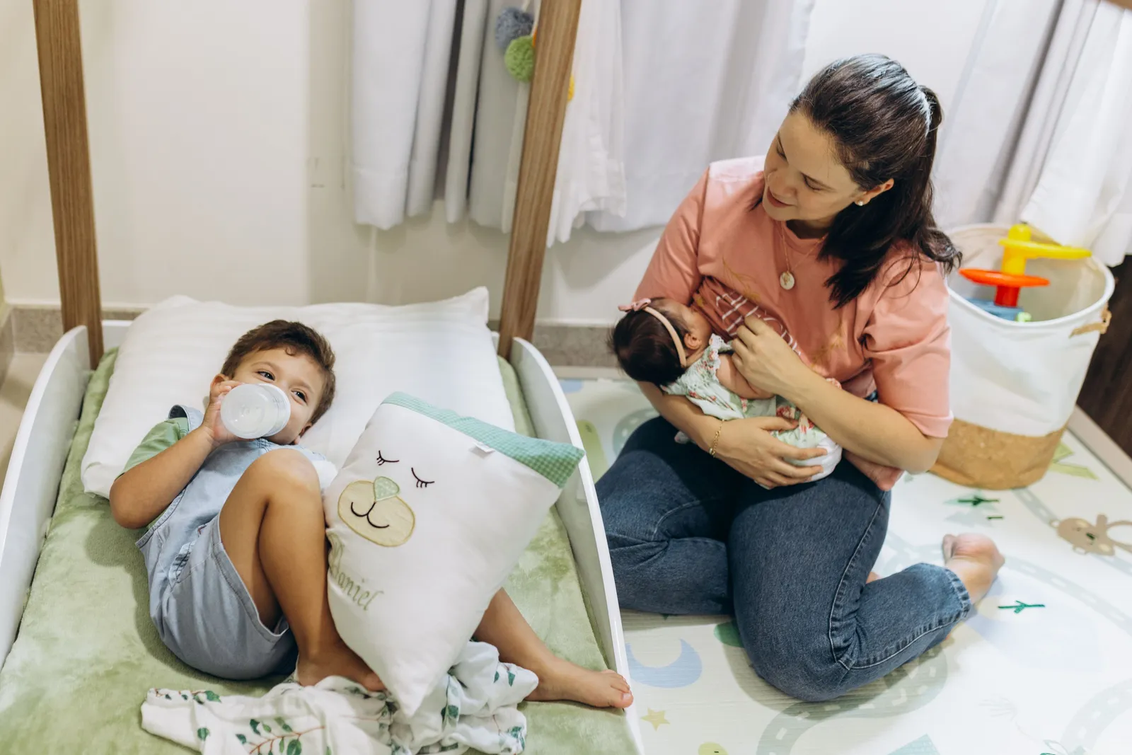 Mãe com bebê e criança pequena em ambiente de berçário acolhedor