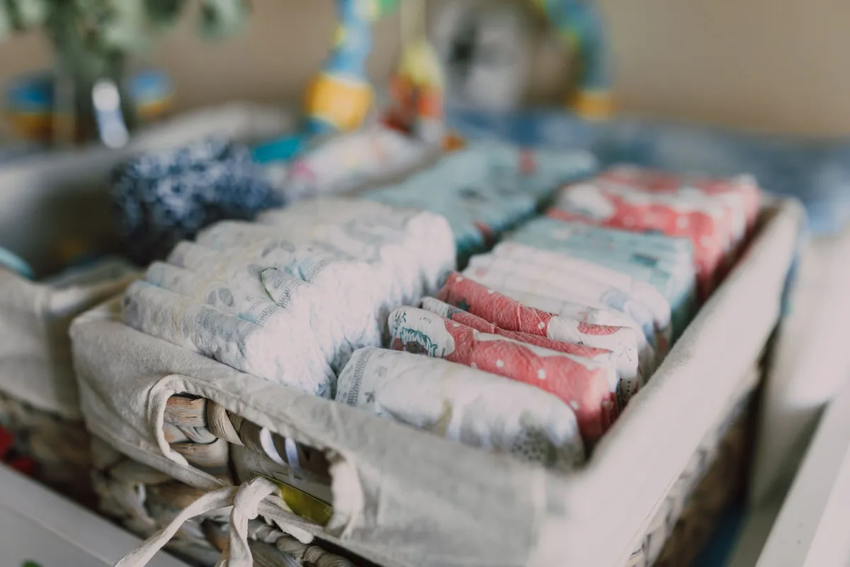 Cesta de vime com fraldas descartáveis de várias estampas empilhadas, na categoria Fraldas da Mamii